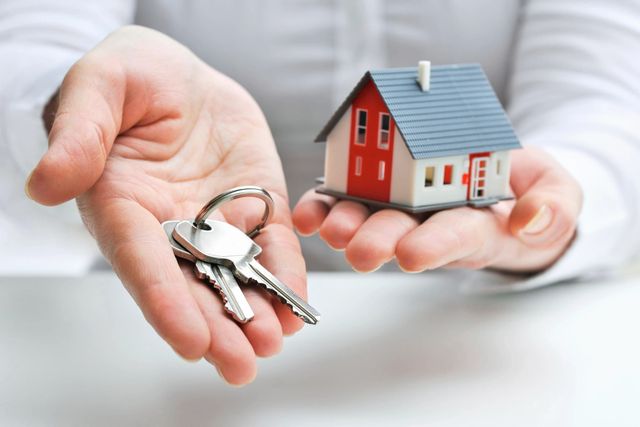 A person holding out their keys to a house.