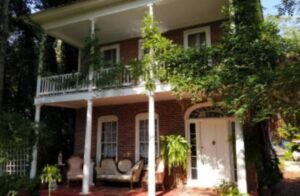 White porch with brick columns and greenery.