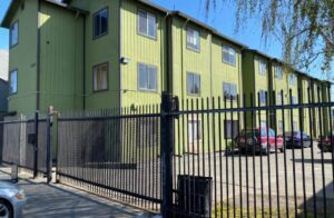 Green apartment building with a fence.