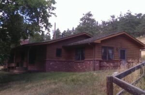 Wooden cabin with brick foundation and trees.