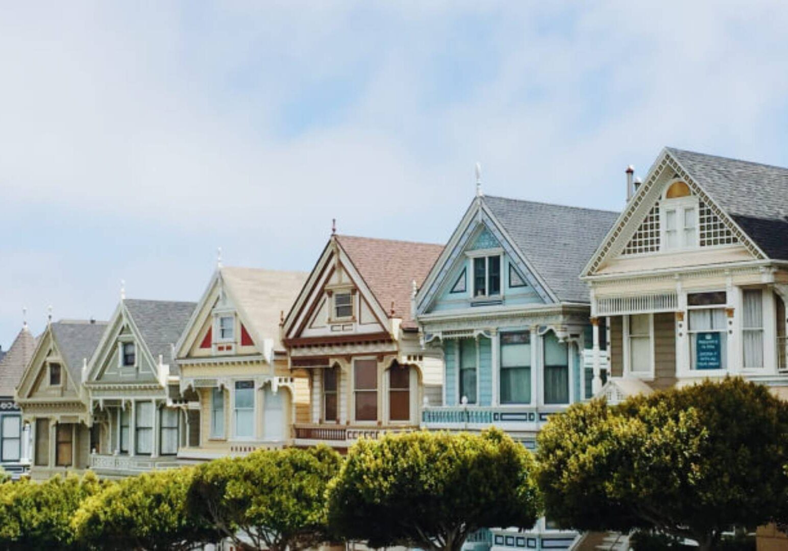 A row of houses with trees in the foreground.