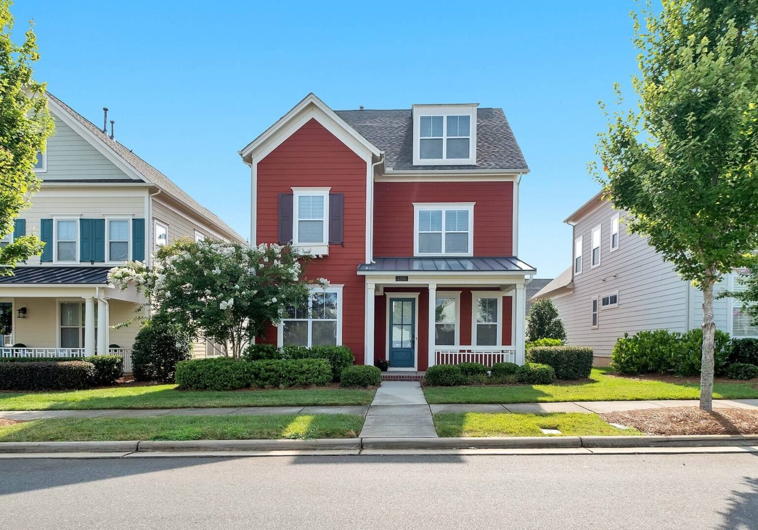 A red house with green grass on the front lawn.